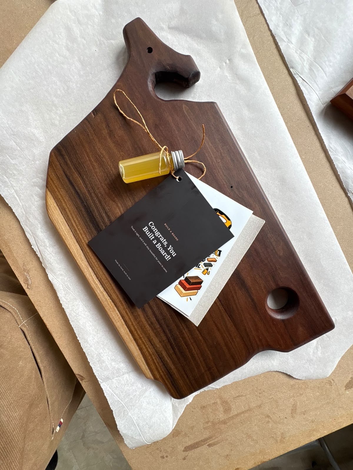 A finished walnut board with its care kit: finishing oil, instruction card and sandpaper
